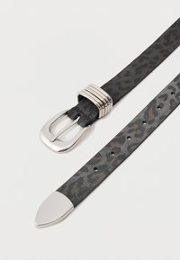 Cinturón de cuero en negro con un sutil estampado de leopardo, que presenta una hebilla plateada y acentos metálicos. Textura suave y punta puntiaguda.