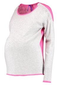 Vaaleanharmaa pitkähihainen paita, jossa on vaaleanpunaiset yksityiskohdat hartioissa ja kaula-aukoissa. Pehmeä, joustava kangas, joka on muotoiltu kasvavalle vatsalle.