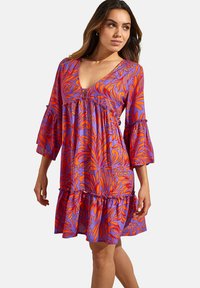 Bloemendruk jurk in paars en oranje, met een V-hals, gerimpelde mouwen en een gelaagde zoom, gemaakt van lichte stof.