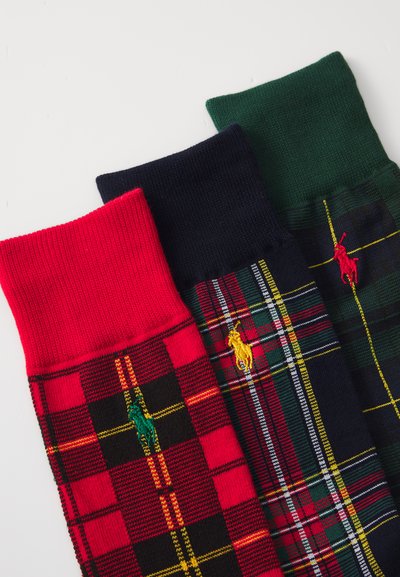 Tre paia di calze: a quadri rossi, a quadri blu navy e verde scuro, con bordi a costina e loghi ricamati in giallo, verde e rosso.