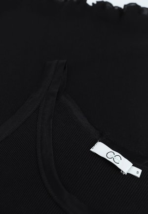 Top débardeur noir à côtes avec des bretelles fines et un col festonné, comportant une étiquette blanche avec le logo de la marque et la taille "S" sur le côté intérieur.