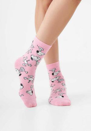 Rosa Baumwollsocken mit wiederholten schwarzen und weißen Cartoon-Hundemotiven, die verspielte Muster und einen weichen, gerippten Bund zeigen.