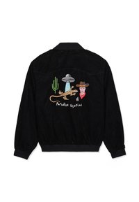 Veste noire avec un cactus vert brodé, un soucoupe volante projetant de la lumière sur un lézard, un visage de cowboy, et le texte "Paradise Utopias" au dos.