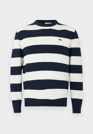 Maglione a righe blu navy e bianche con collo a giro, realizzato in tessuto a maglia. Presenta polsini e orlo a coste, con un piccolo logo ricamato sul petto.