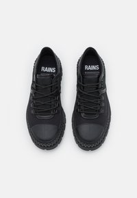 Zapatillas negras con parte superior de tejido texturizado, puntera de goma y suela de goma gruesa que presenta un patrón de banda de rodadura. Los cordones son circulares y oscuros.