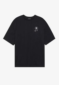 T-shirt de algodão preto com mangas curtas, apresentando um pequeno gráfico de flor branca bordado no lado esquerdo do peito. Gola clássica em crew.