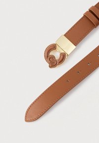 Rudas odinis diržas su auksine kvadratine sagtimi, puošta rudu susipynusiu raštu. Lygus paviršius su matomomis siūlėmis ir reguliuojamomis skylutėmis.