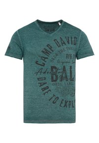 Camiseta de rayas verdes hecha de algodón. Presenta un escote en V, mangas cortas y gráficos impresos en diseño de texto marrón oscuro en la parte delantera.