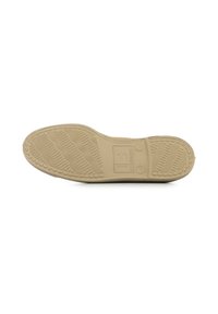 Semelle en caoutchouc beige avec des motifs de texture pour une meilleure adhérence, marquée d'un logo et de détails de taille, présentant une forme plate et des bords légèrement surélevés.