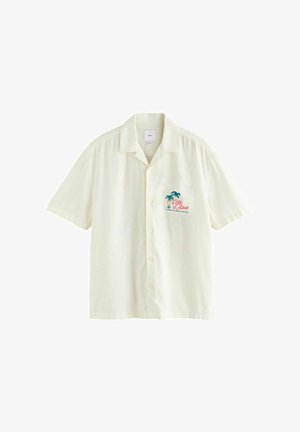 Chemise crème à manches courtes avec boutons, col, motif palmier sur la poitrine et texte rouge « Côte d'Azur » sur le côté gauche devant.