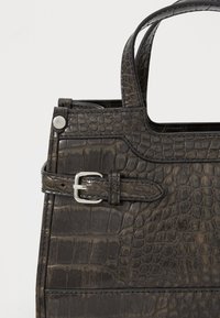 Sac à main en cuir d'alligator noir chocolat avec des poignées doubles et une boucle argentée, présentant une texture lisse et une forme structurée.