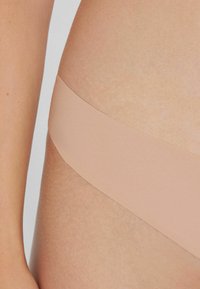 Nude seamless bielizna osobista o gładkiej, miękkiej fakturze. Minimalistyczny styl z cienkim, elastycznym paskiem.