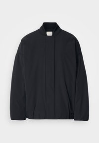 Veste légère noire à manches longues, col montant, fermeture avant dissimulée et logo Calvin Klein subtil près de l'ourlet.