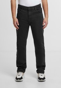 Jeans negri din denim cu o croială dreaptă, având un design clasic cu cinci buzunare și detalii de cusătură subtile. Asortați cu adidași albi.