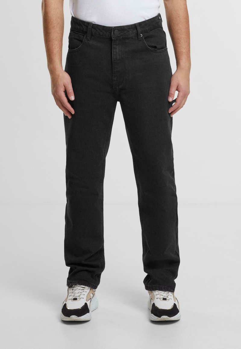 Jeans negri din denim cu o croială dreaptă, având un design clasic cu cinci buzunare și detalii de cusătură subtile. Asortați cu adidași albi.