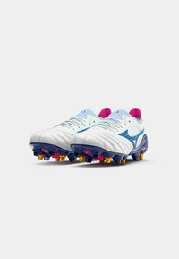 White soccer cleats with blue accents and pink heel detail. Textured upper with multi-colored studs, including yellow, black, and purple.