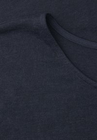Tissu bleu marine foncé plié pour montrer une texture de maille fine et lisse ainsi qu'un col arrondi avec un bord cousu.