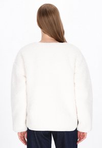 Weißer, flauschig strukturierter übergroßer Pullover. Rundhalsausschnitt und überschnittene Schultern mit langen Ärmeln. Einfaches, klares Design ohne sichtbare Verschlüsse.