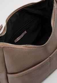 Borsa in pelle taupe con zip aperta che mostra l'interno in tessuto nero e una tasca interna con zip con etichetta del marchio Anna Field.