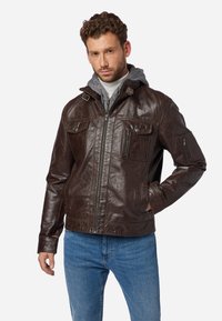 Braune Lederjacke mit Reißverschluss, vier Taschen und strukturiertem Finish. Dazu gehört ein grauer Kapuzenpullover und lässige blaue Jeans.