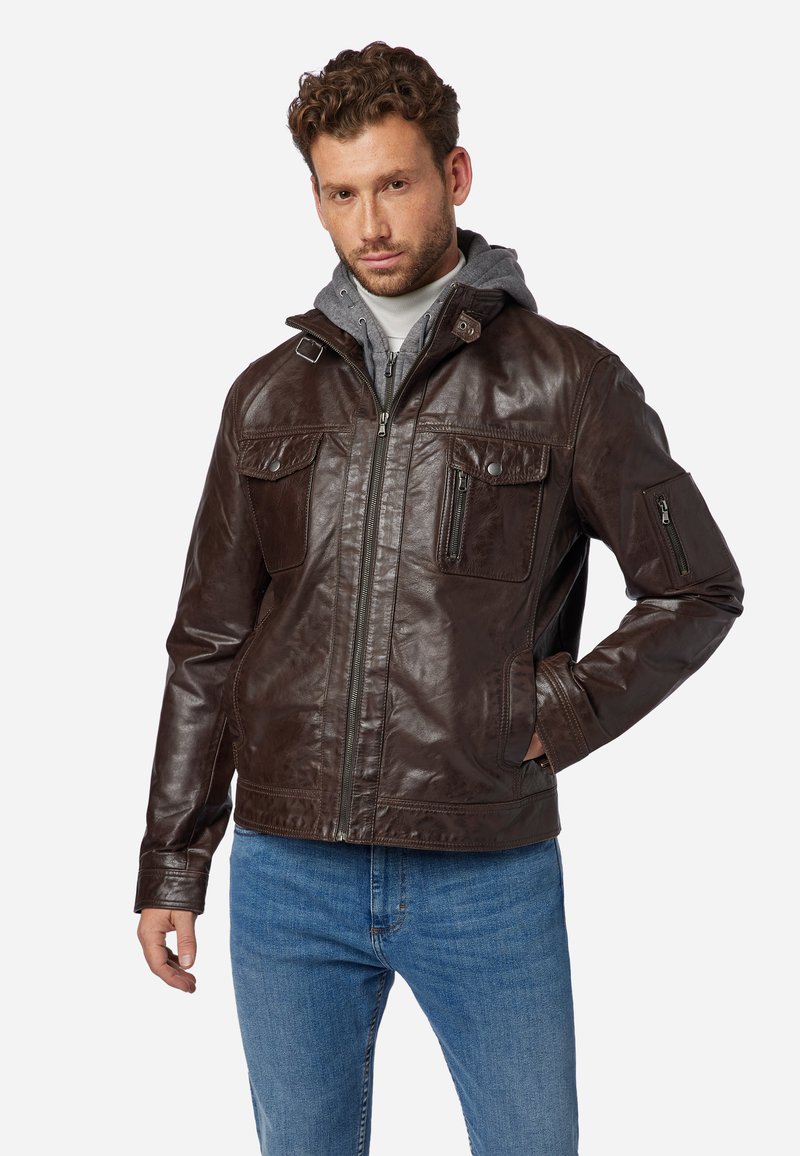 Braune Lederjacke mit Reißverschluss, vier Taschen und strukturiertem Finish. Dazu gehört ein grauer Kapuzenpullover und lässige blaue Jeans.