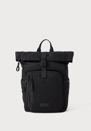 Černý rolovací batoh vyrobený z odolného nylonu, s přední kapsou na zip, boční kapsou a nastavitelnými popruhy. Minimalistický design s matným povrchem.