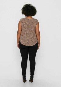 Koszulka bez rękawów w kwiatowy wzór w odcieniach brązu i fioletu. Połączona z czarnymi obcisłymi dżinsami i botkami za kostkę. Zaokrąglony dół.