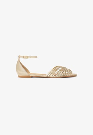 Sandali piatti d'oro con punta aperta e design superiore intrecciato, dotati di una sottile fascia alla caviglia e texture in pelle liscia.