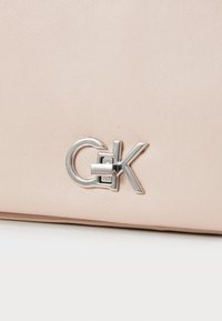 Borsa a tracolla in pelle rosa con un'accattivante accentuazione in metallo argento e una superficie texturizzata. Design compatto con linee pulite e decorazioni minime.