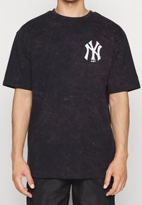 Černé oversized tričko vyrobené z měkké bavlněné tkaniny, s bílým logem "NY" na levém hrudníku. Texturovaný, minerálně praný vzhled.