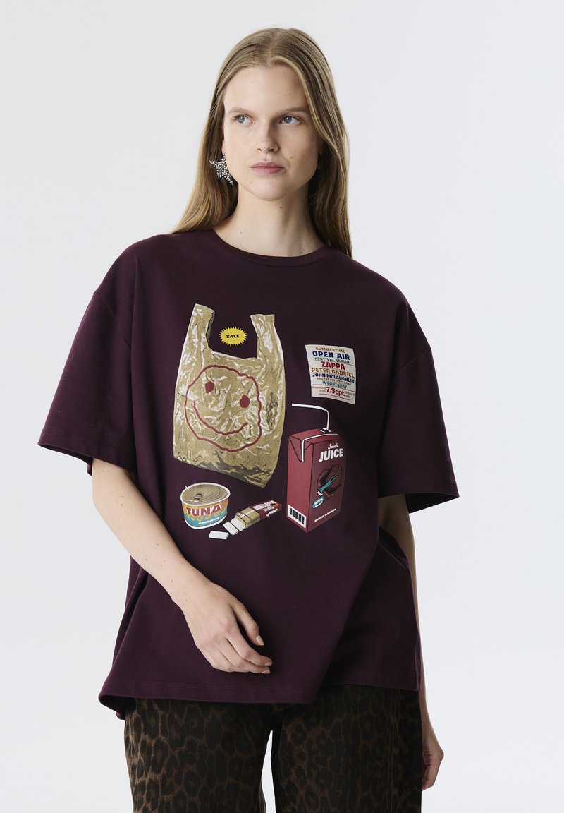 Camiseta de gran tamaño en color marrón burdeos que presenta una impresión gráfica de una bolsa de plástico con una cara sonriente, ilustraciones de atún enlatado y una caja de zumo.