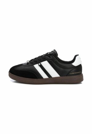 Zapatillas negras con rayas blancas, parte superior de nobuk y cuero, diseño de perfil bajo, suela de goma texturizada y detalle de marca en el talón.