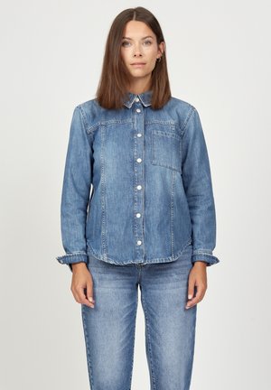 Denim shirt in light blue. Features a button-up front, collar, single chest pocket, and cuffed sleeves with a frayed edge.