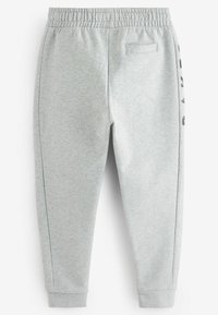Pantalones de chándal de algodón gris con cintura elástica, bolsillos laterales y detalle de logo negro a lo largo de la pierna izquierda.