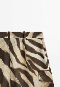 Pantalon taille haute avec passants de ceinture et poche latérale, présentant un motif zèbre marron et beige sur un tissu léger.