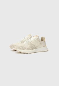 Beige joggesko med teksturert stoffoverdel, mønstrede detaljer, hvite snører og gullfiner på hælen og tungen. Lett gummisåle.