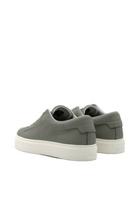 Sneaker in pelle grigia con design a basse, texture liscia, suola in gomma bianca e branding discreto sul tallone.