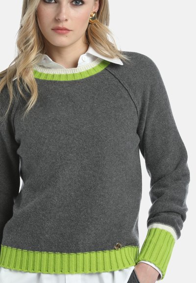 Pull en laine gris avec des poignets et un ourlet côtelés verts, avec un col texturé blanc en dessous. Détail en accent or près de l'ourlet.