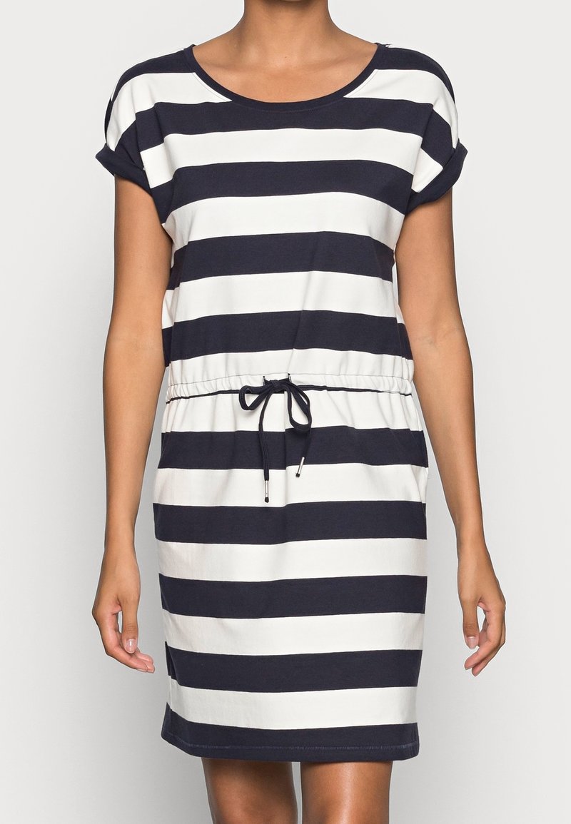 Femme portant une robe à manches courtes, longueur genou, avec de larges rayures horizontales bleu marine et blanches et une taille à cordon.