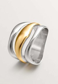 Anillo de plata y oro con bandas de metal curvas. El diseño incluye una franja dorada suave flanqueada por dos bandas de plata brillantes.