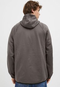 Felpa grigia con cappuccio, dal tessuto liscio, maniche raglan e vestibilità comoda. Presenta un design minimalista senza motivi o accenti.