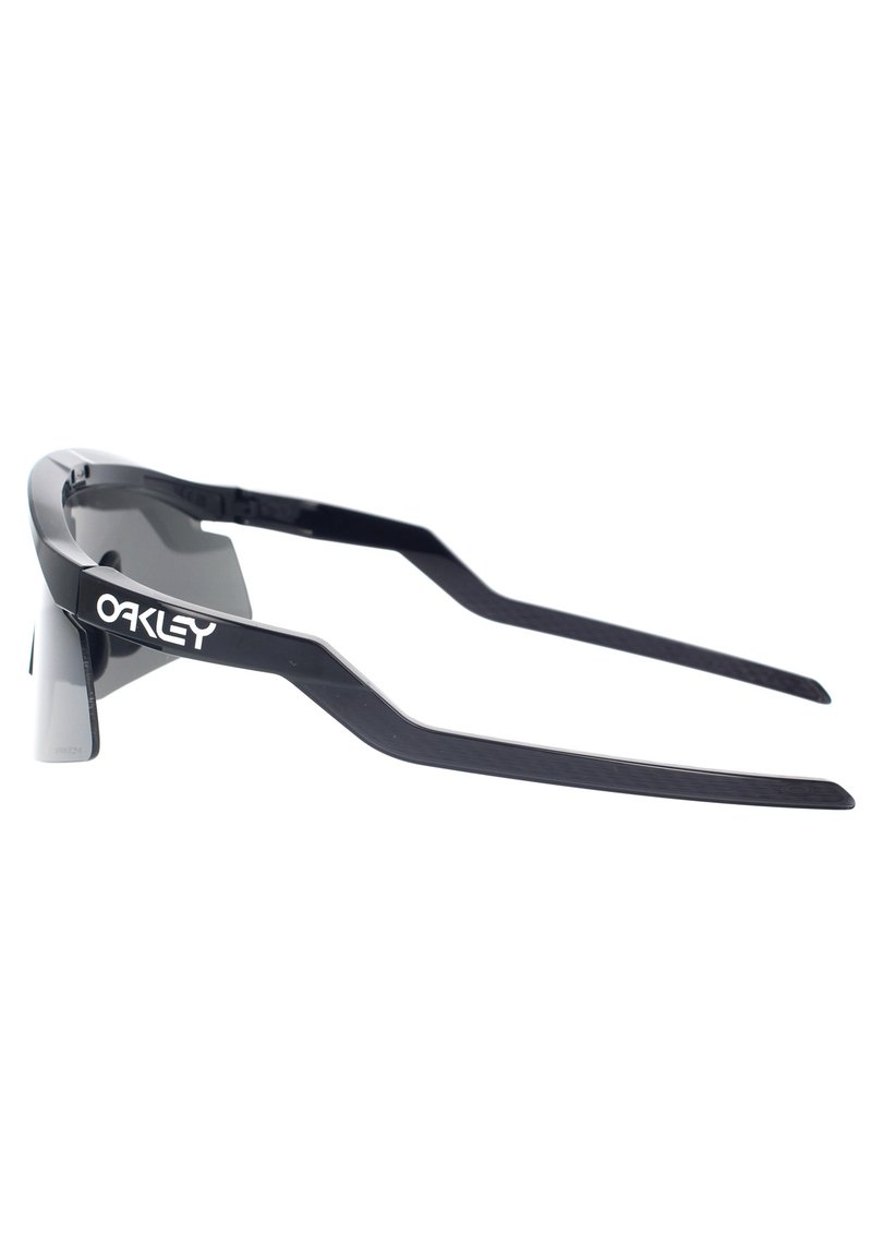 Occhiali da sole neri Oakley con un design elegante, bracci allungati e lenti scure. Caratterizzati da un logo minimale e una forma del telaio angolare.