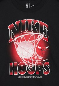 Juodas marškinėliai su grafiniu dizainu, kuriame raudonai ir baltai parašyta „NIKE HOOPS“, krepšinis tinkle ir Čikagos „Bulls“ logotipas.
