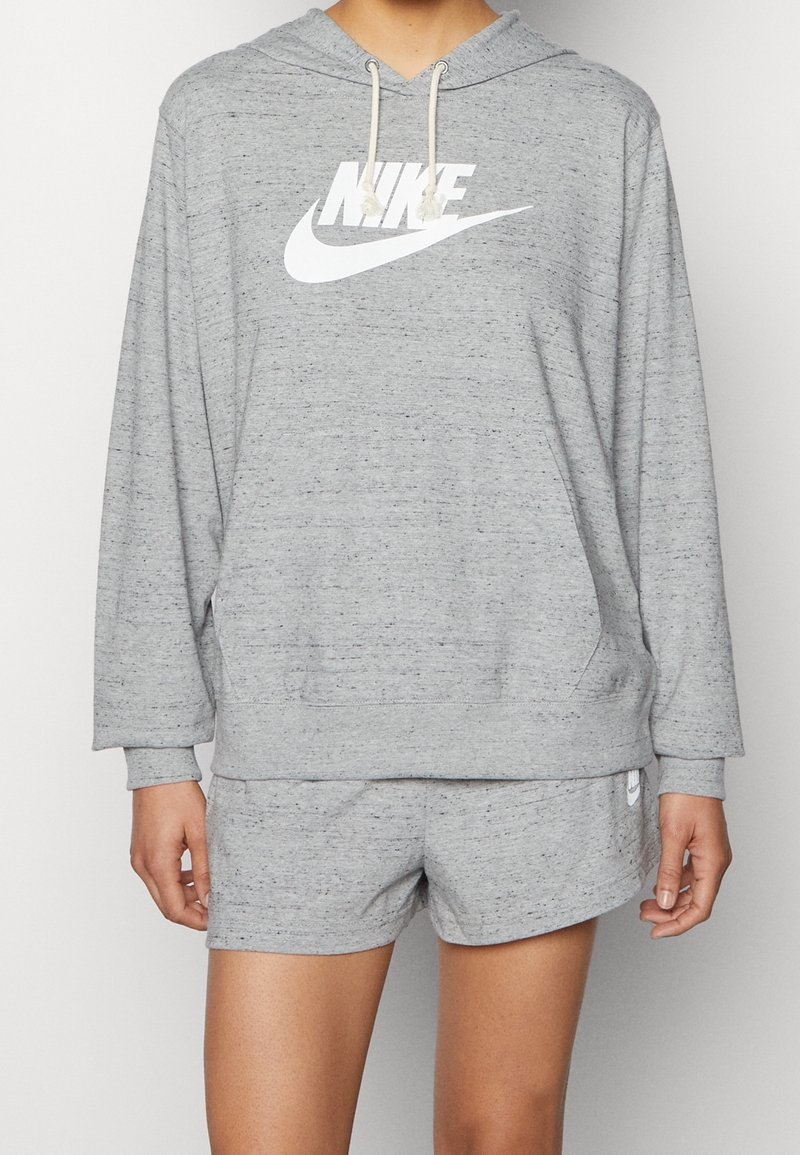 Gray hoodie with white Nike logo, drawstring hood, and kangaroo pocket. Paired with matching gray shorts, both featuring a soft texture.
