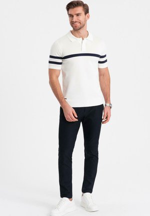 Biała koszulka polo w granatowe poziome paski, krótki rękaw. Połączona z ciemnymi spodniami i białymi sneakersami. Prosty design, lekka tkanina.