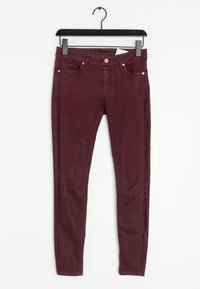 Jeans skinny bordeaux realizzati in tessuto misto cotone, con design classico a cinque tasche e dettagli in metallo color rame.