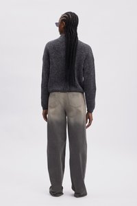 Gray knitted sweater with a high neck, paired with light gray, loose-fitting jeans featuring a subtle ombre effect and unique back pocket design.