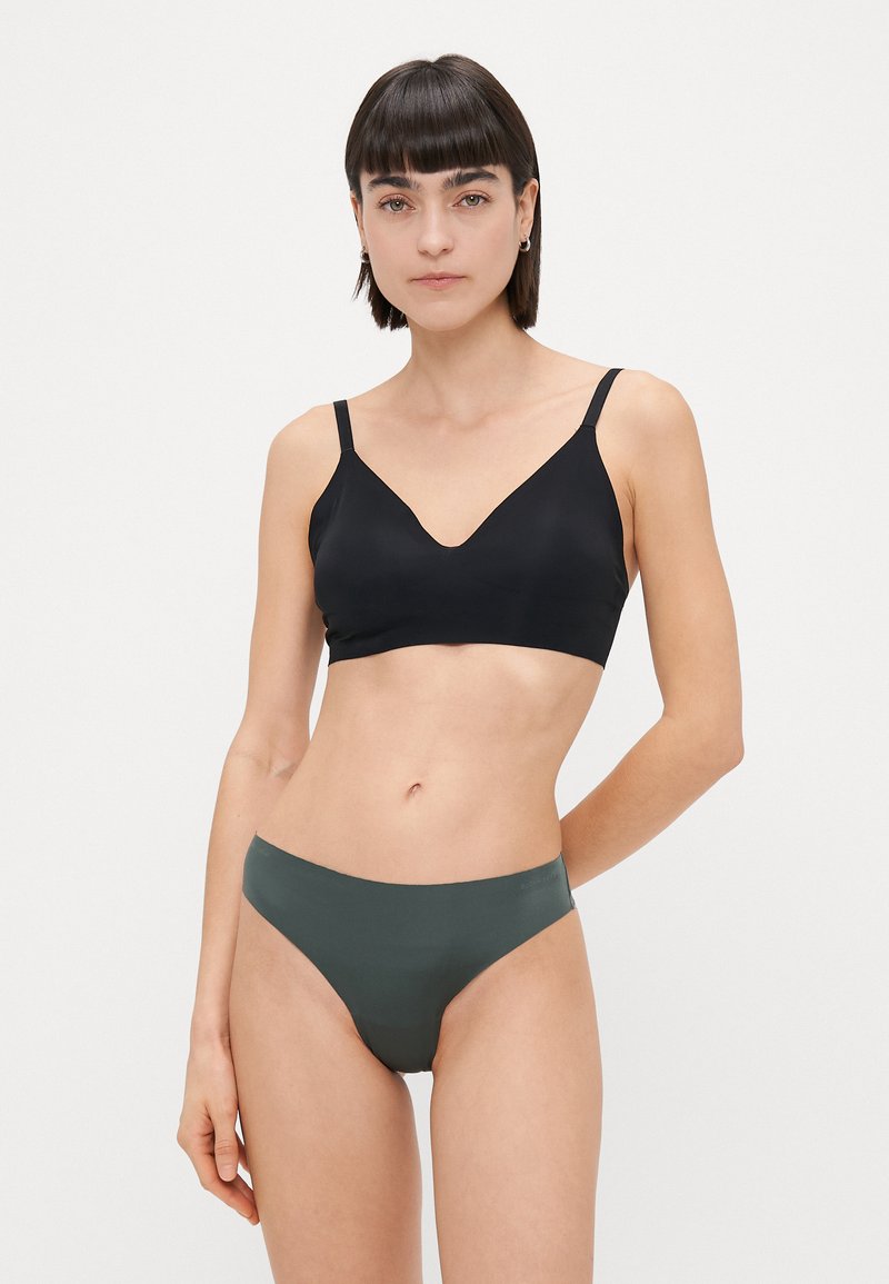 Fekete, varrás nélküli bralette V-nyakkal és állítható pántokkal, olíva zöld, alacsony derekú bikini alsóval párosítva. Sima textúra, modern fazon.