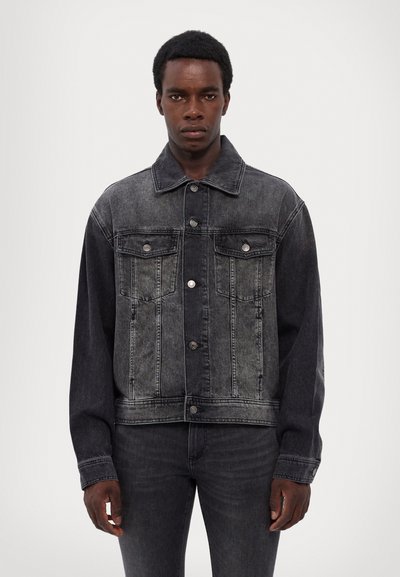 Black denim jacket with a faded finish, front pockets, button closure, and long sleeves, paired with matching black jeans.