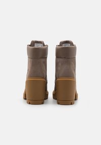 Brown leather ankle boots with a high heel and rubber sole, featuring a rounded toe and padded collar. Detailing includes brand tag inside.